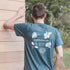 Back view of a man wearing an EightBillion t-shirt with eco-conscious branding. The shirt highlights the slogan ‘Drink Good, Feel Good, Do Good’ with graphics of coffee, mushrooms, and botanicals.