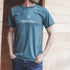 Front view of a man wearing an EightBillion t-shirt with eco-conscious branding. The shirt highlights the slogan ‘Drink Good, Feel Good, Do Good’ with graphics of coffee, mushrooms, and botanicals.
