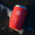 Red EightBillion reusable coffee cup with eco-friendly design resting by the ocean shore. Sustainable mushroom coffee lifestyle for wellness and reducing waste