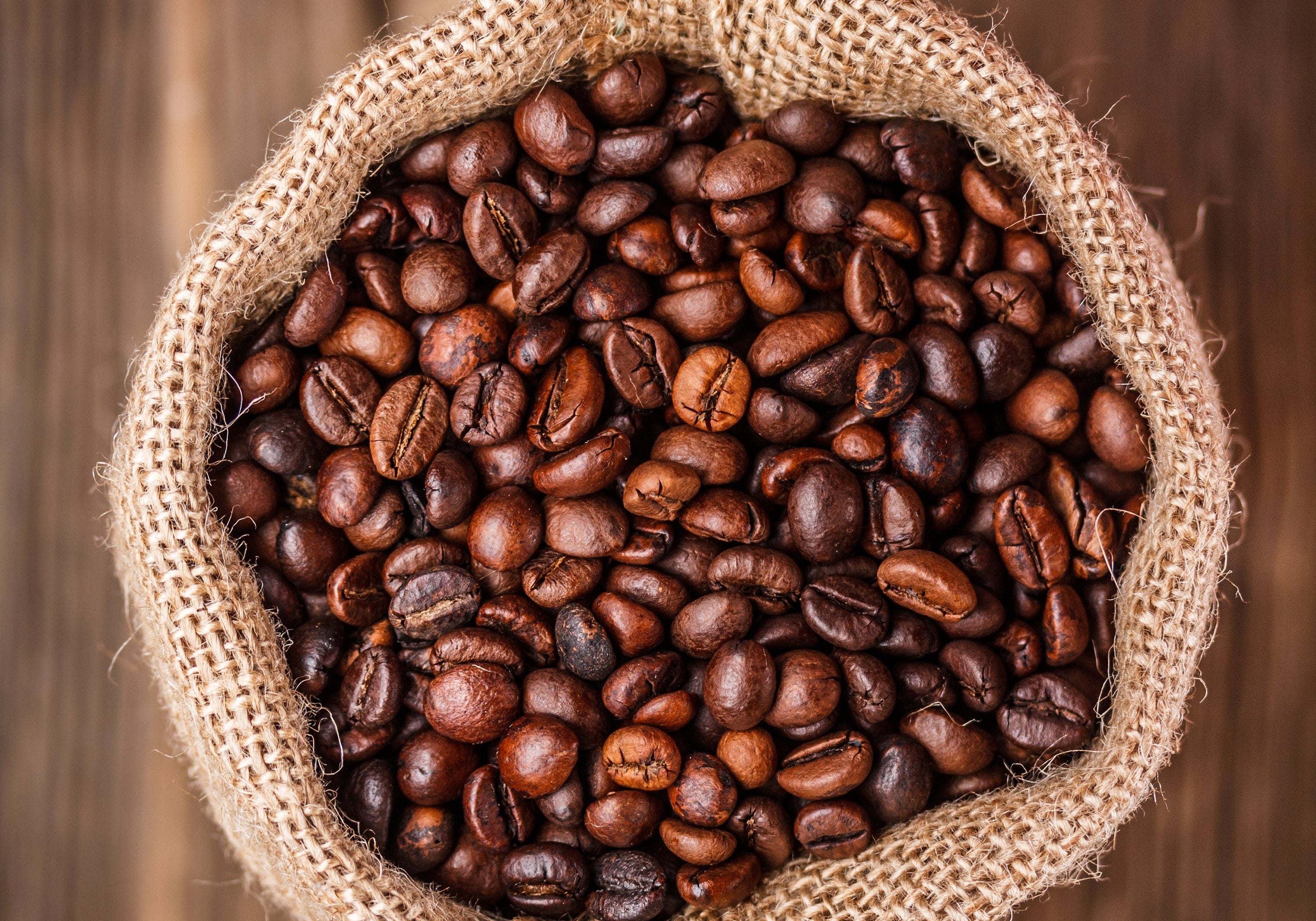 Close-up of organic roasted coffee beans in a burlap sack, ready for grinding. Premium Arabica Colombian coffee used in EightBillion’s JostArriba mushroom coffee blend for rich flavor and natural energy.